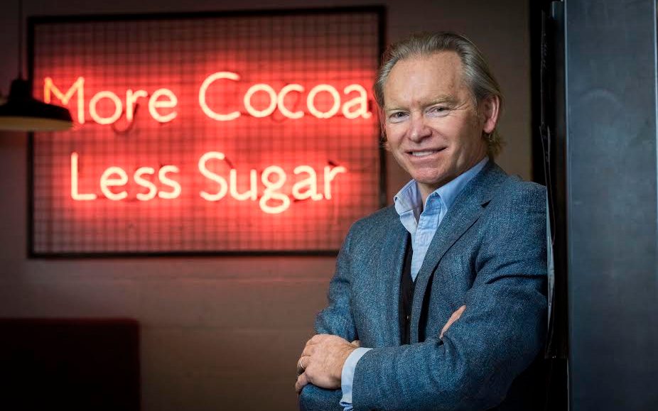 Image of Hotel Chocolat CEO with More Cocoa Less Sugar neon sign | Velvetiser